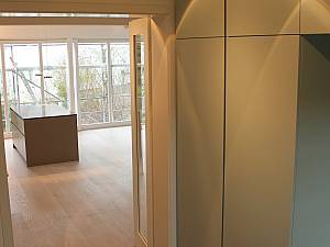 Deckenleuchten Occhio, Wandeinbauschränke farblich auf Via Fliesen abgestimmt, Randfries um florale Fliesen, Teppicheffekt. 