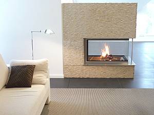 Brunner Kamin, 3-seit Gerät, mit schariertem Kalkstein verkleidet.